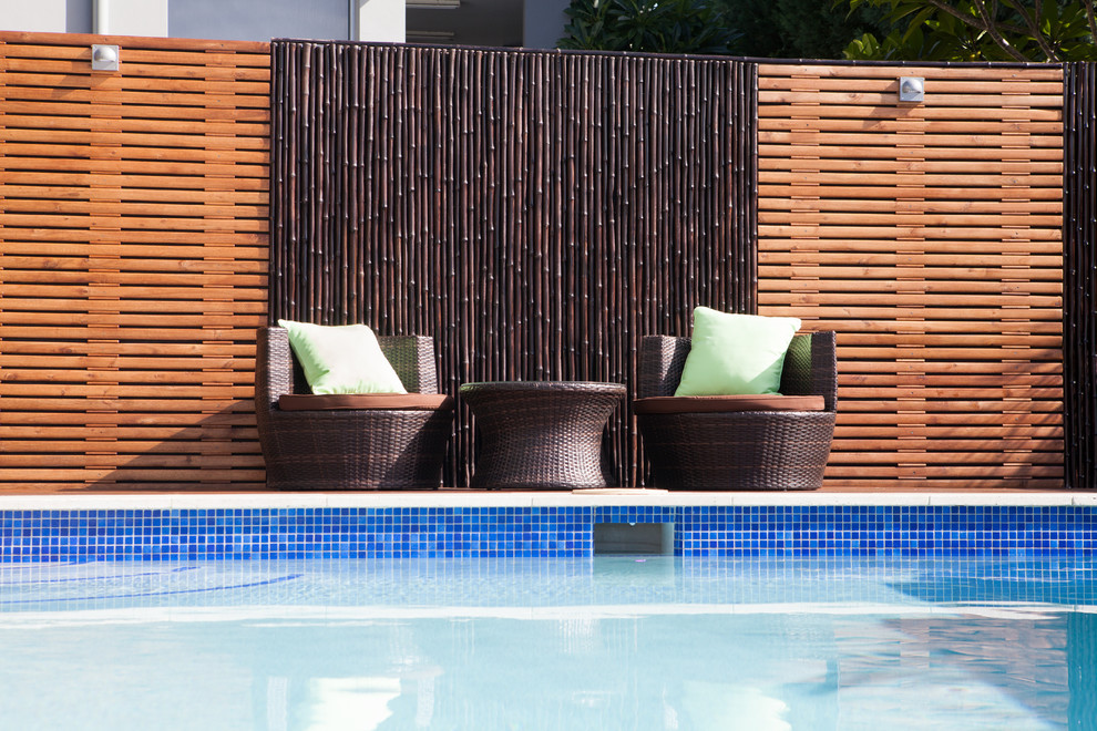 Ispirazione per una piscina naturale design rettangolare di medie dimensioni e dietro casa con fontane e piastrelle