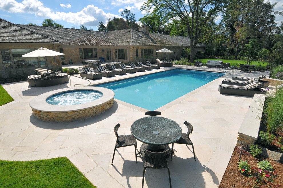 Ejemplo de piscinas y jacuzzis alargados tradicionales de tamaño medio rectangulares en patio trasero con adoquines de piedra natural