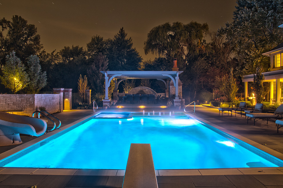 Ejemplo de piscinas y jacuzzis alargados clásicos de tamaño medio rectangulares en patio trasero con adoquines de piedra natural