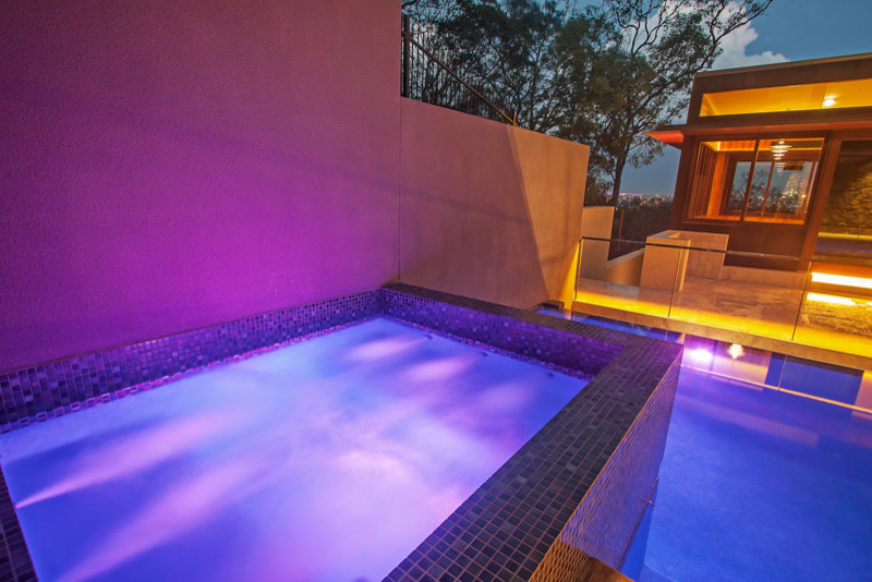 Immagine di una piscina a sfioro infinito design rettangolare di medie dimensioni e in cortile con una vasca idromassaggio e piastrelle