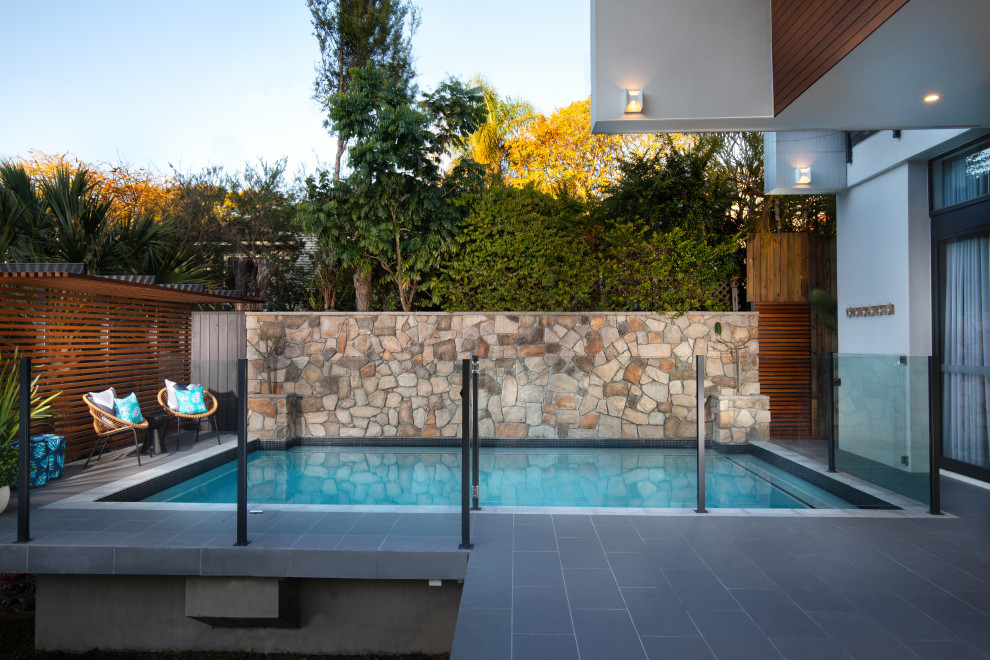 На фото: прямоугольный бассейн среднего размера на заднем дворе в современном стиле с покрытием из плитки с