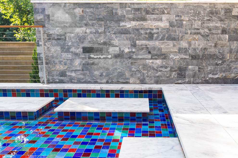 Immagine di una piscina a sfioro infinito moderna a "L" di medie dimensioni e dietro casa con pavimentazioni in pietra naturale