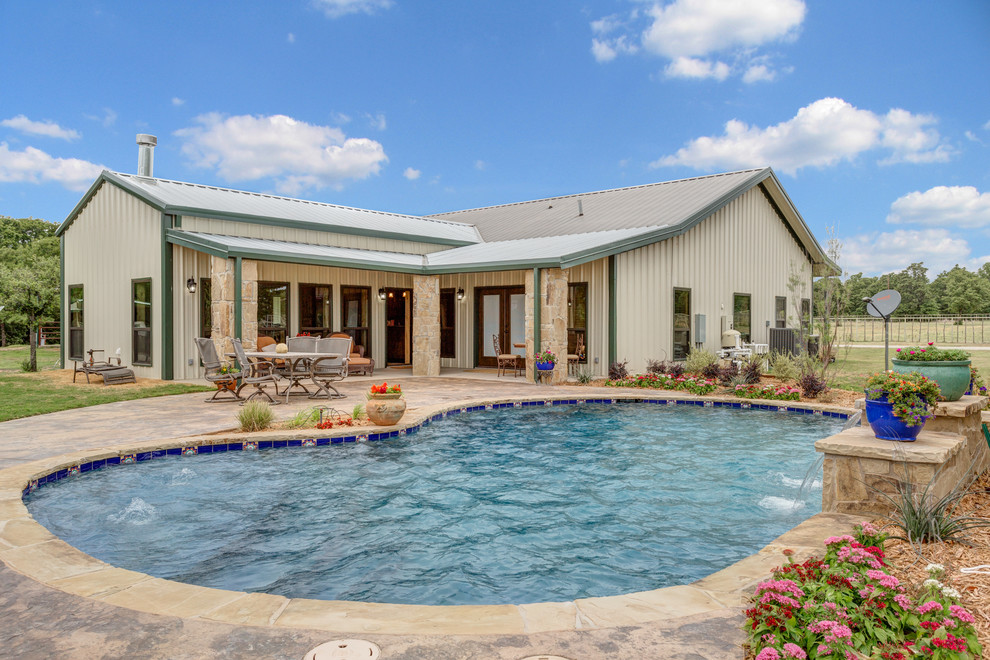 This is an example of a medium sized classic back kidney-shaped lengths swimming pool in Dallas with a water feature and natural stone paving.