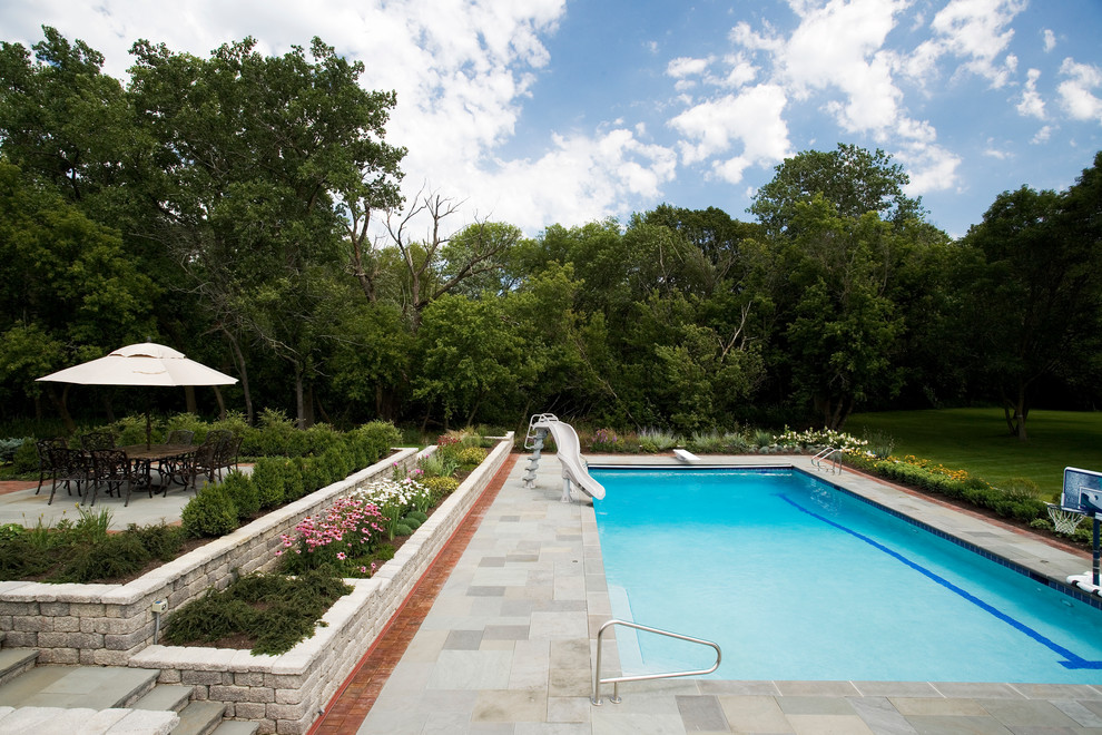 Immagine di una grande piscina monocorsia stile rurale rettangolare dietro casa con pavimentazioni in pietra naturale