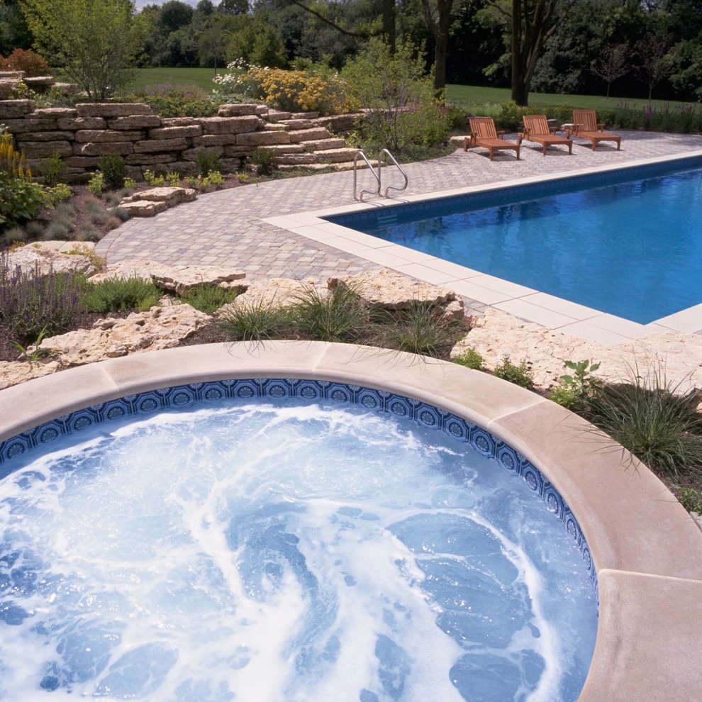 Ispirazione per una piscina monocorsia classica rettangolare di medie dimensioni e dietro casa con una vasca idromassaggio e pavimentazioni in cemento