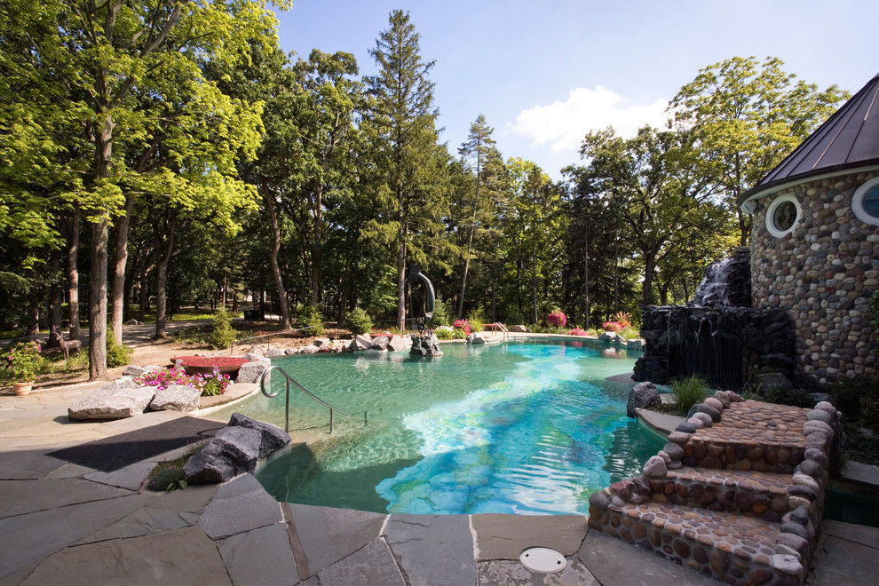 Idee per un'ampia piscina a sfioro infinito mediterranea personalizzata dietro casa con pavimentazioni in pietra naturale e una vasca idromassaggio