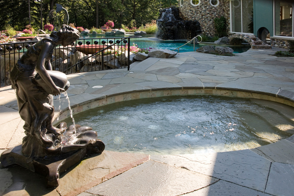 Inspiration for a huge mediterranean backyard stone and custom-shaped infinity hot tub remodel in Chicago