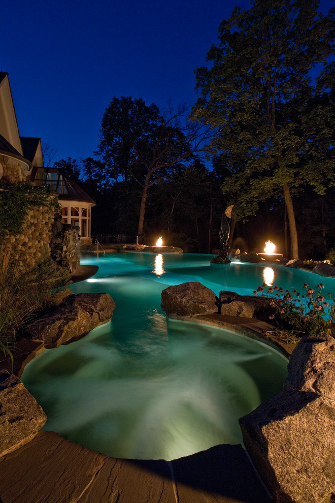Idee per un'ampia piscina a sfioro infinito mediterranea personalizzata dietro casa con pavimentazioni in pietra naturale e una vasca idromassaggio