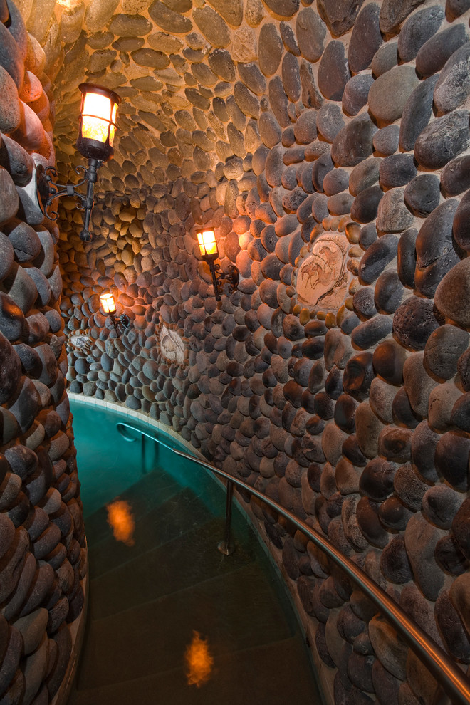 Ispirazione per un'ampia piscina coperta mediterranea personalizzata con pavimentazioni in pietra naturale e una vasca idromassaggio
