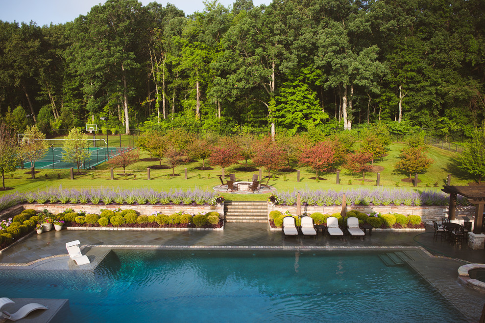 Ejemplo de casa de la piscina y piscina infinita clásica grande a medida en patio trasero con adoquines de piedra natural