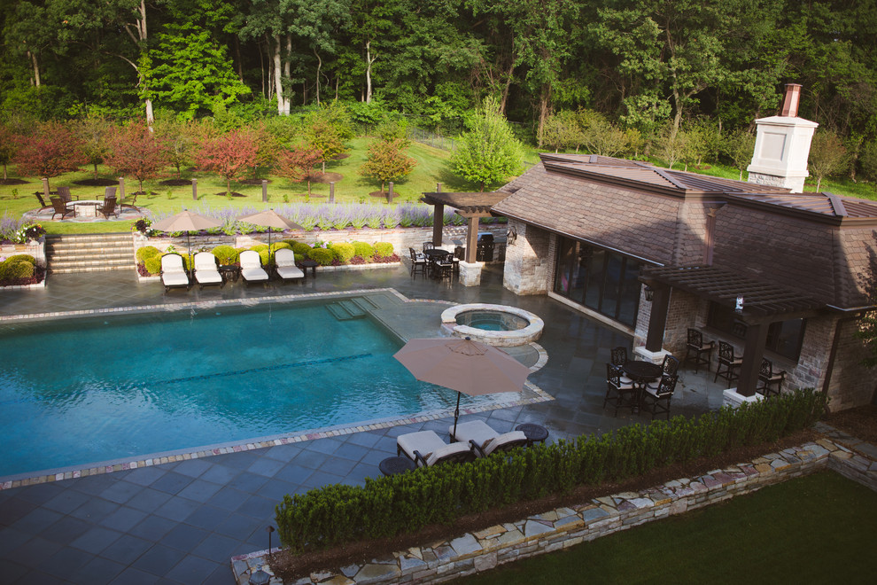 Foto di una grande piscina a sfioro infinito chic personalizzata dietro casa con una dépendance a bordo piscina e pavimentazioni in pietra naturale