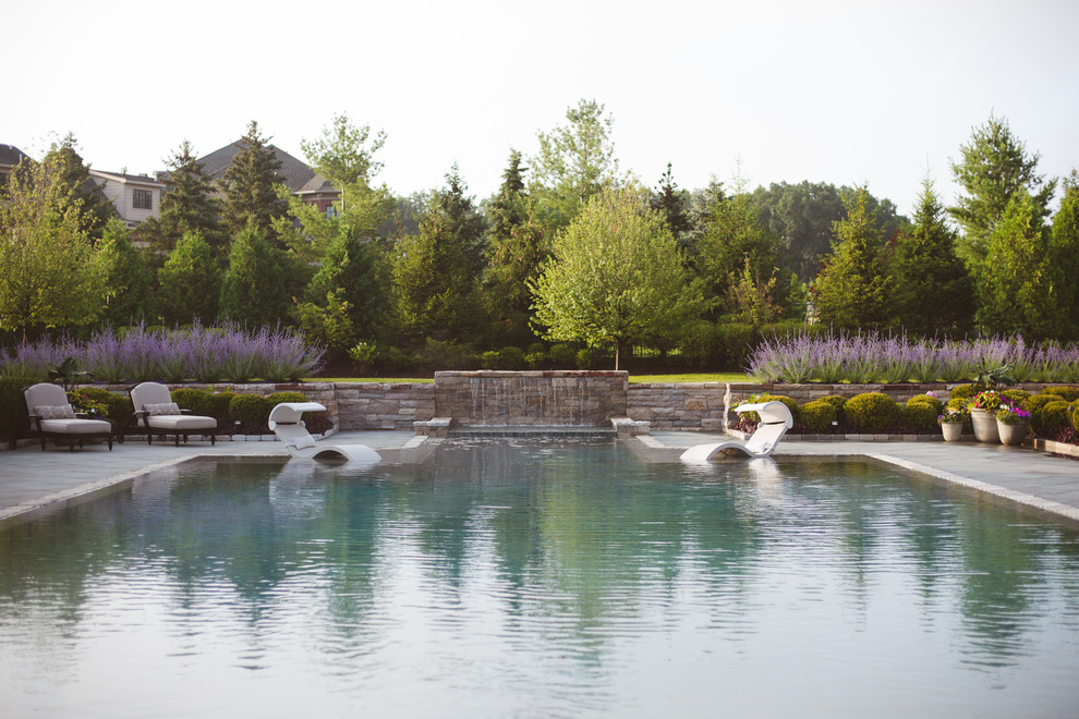 Diseño de casa de la piscina y piscina infinita clásica grande a medida en patio trasero con adoquines de piedra natural
