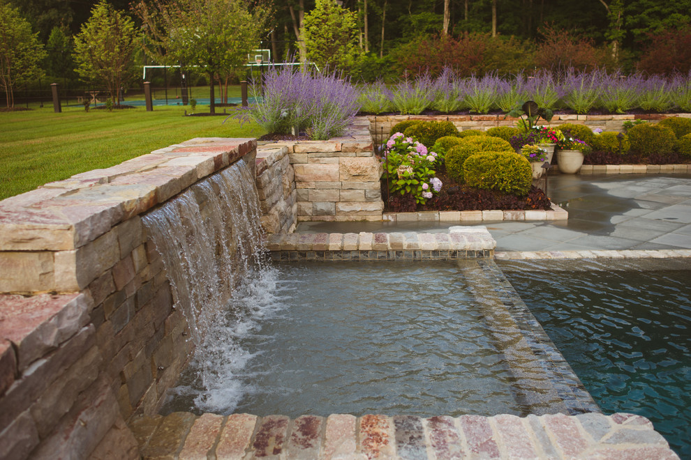 Imagen de casa de la piscina y piscina infinita clásica grande a medida en patio trasero con adoquines de piedra natural