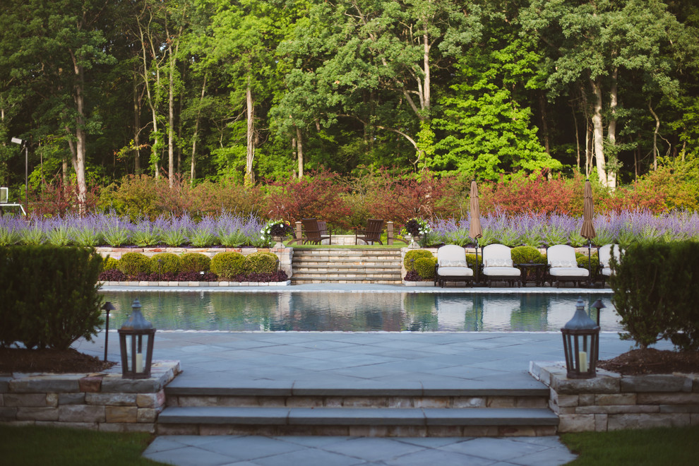 Ejemplo de casa de la piscina y piscina infinita tradicional grande a medida en patio trasero con adoquines de piedra natural
