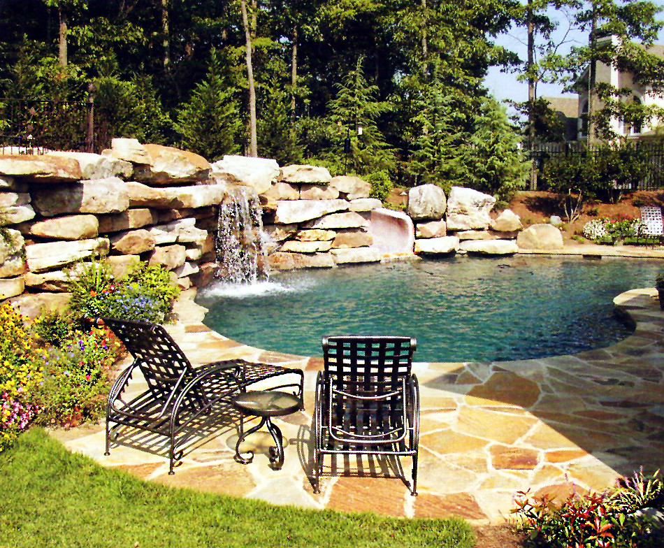 Modelo de piscina con tobogán natural tradicional de tamaño medio tipo riñón en patio trasero con adoquines de piedra natural