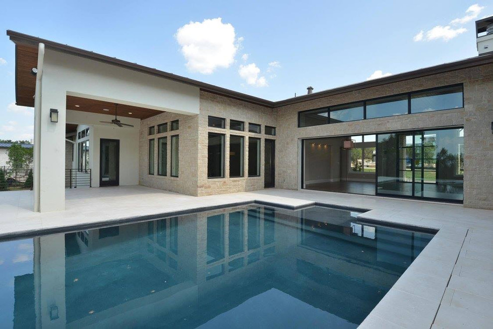 Imagen de piscina alargada actual grande rectangular en patio con adoquines de piedra natural
