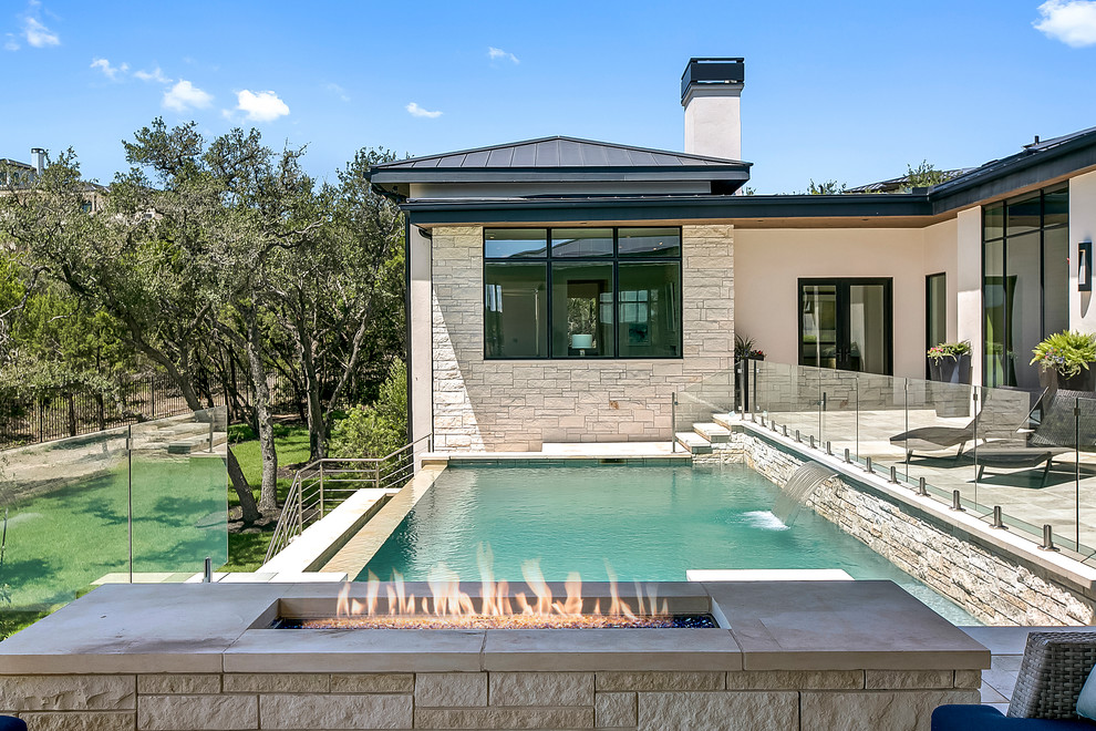 Example of a large trendy backyard rectangular infinity pool design in Austin
