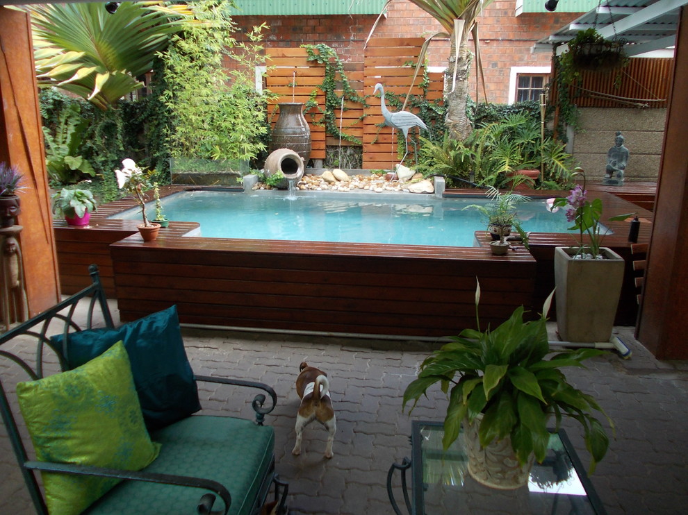 Aménagement d'une piscine hors-sol exotique de taille moyenne et rectangle avec un point d'eau, une cour et une terrasse en bois.