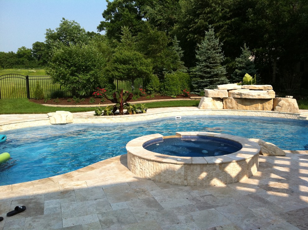Photo of a medium sized world-inspired back custom shaped swimming pool in Chicago with a water feature and natural stone paving.