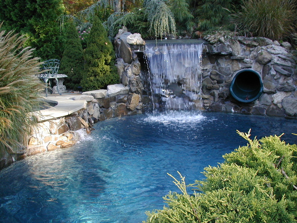 Modelo de piscina con fuente natural tradicional grande redondeada en patio trasero con adoquines de piedra natural