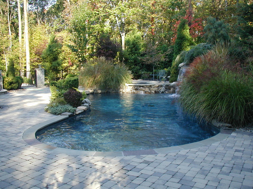 Idées déco pour une grande piscine naturelle et arrière classique ronde avec un point d'eau et des pavés en pierre naturelle.