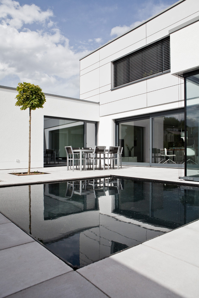 Idee per una piccola piscina moderna rettangolare dietro casa con pavimentazioni in cemento