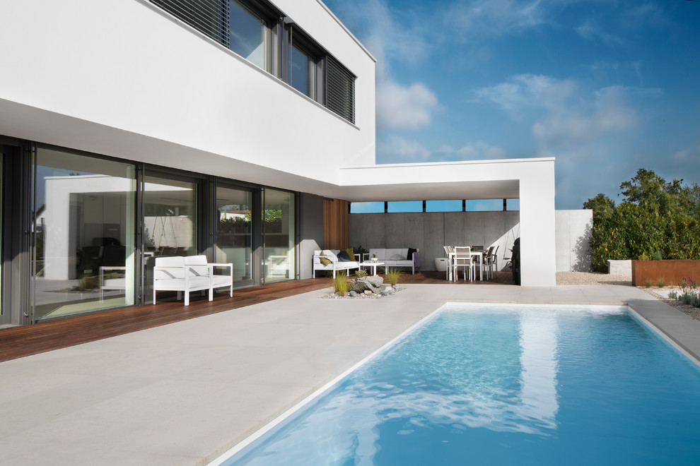 Imagen de piscina alargada moderna grande rectangular en patio trasero con losas de hormigón