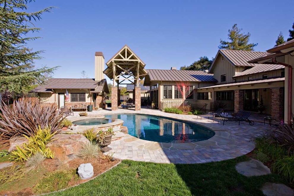Foto de casa de la piscina y piscina natural de estilo de casa de campo grande tipo riñón en patio trasero con adoquines de piedra natural