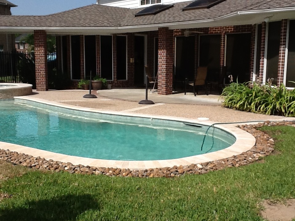 Mid-sized elegant backyard stone and custom-shaped pool photo in Houston