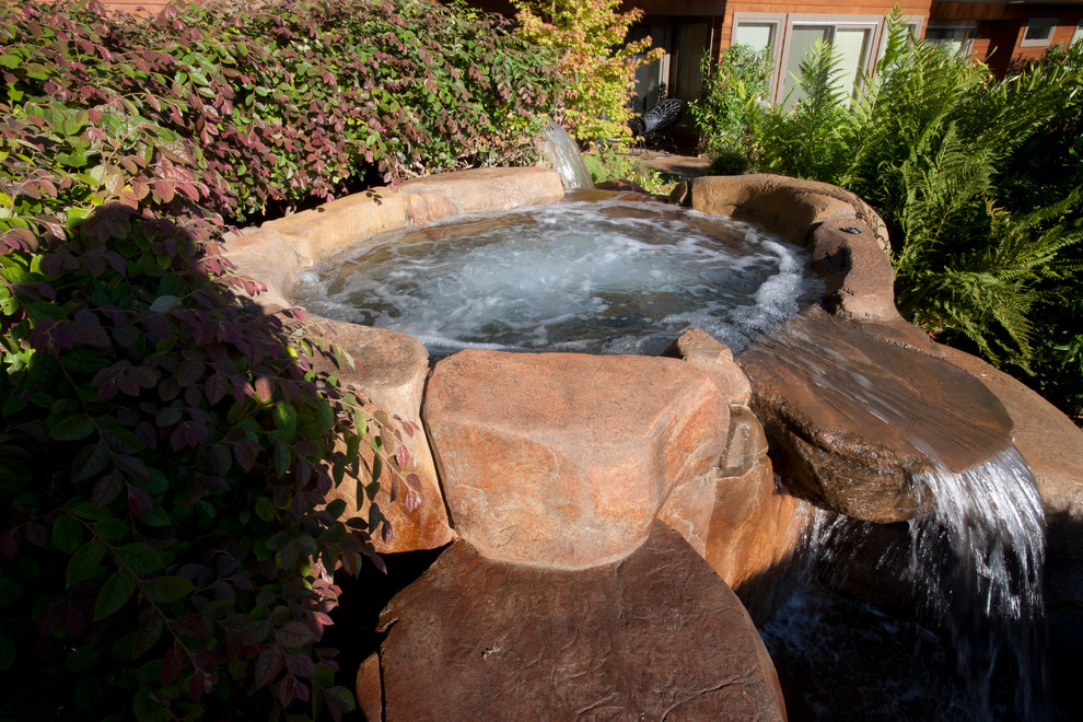 Hot tub - large tropical backyard stone and custom-shaped infinity hot tub idea in San Francisco