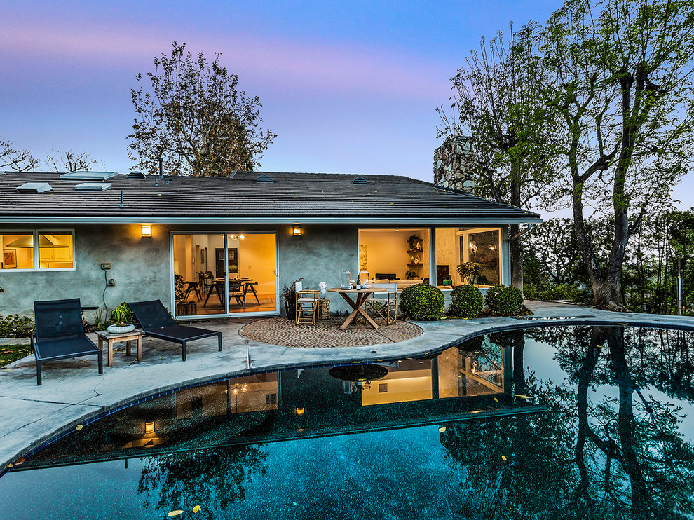Photo of a medium sized contemporary back custom shaped swimming pool in Los Angeles with concrete paving.