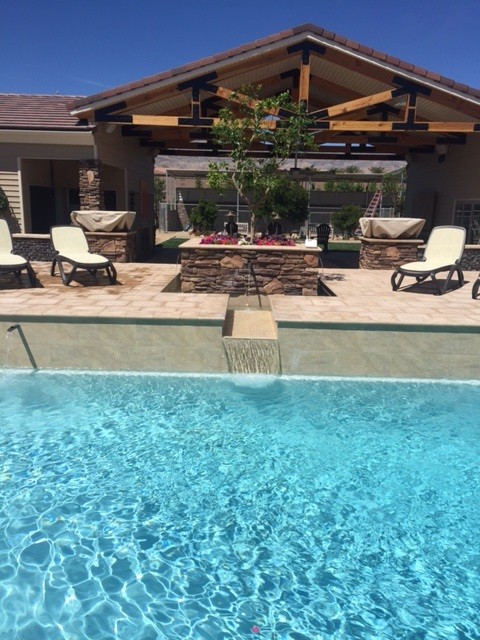 This is an example of a medium sized modern back rectangular swimming pool in Las Vegas with a pool house and brick paving.