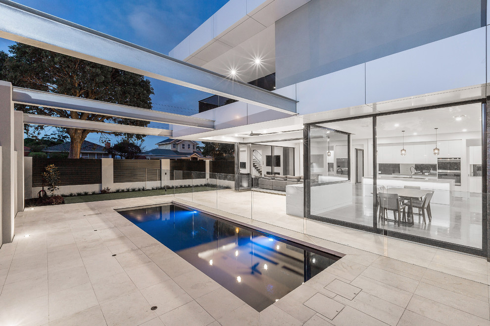 Diseño de piscina con fuente moderna de tamaño medio rectangular en patio lateral con adoquines de hormigón