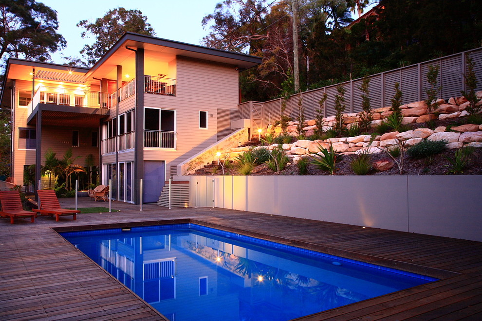 Foto de piscina exótica grande rectangular en patio lateral con entablado