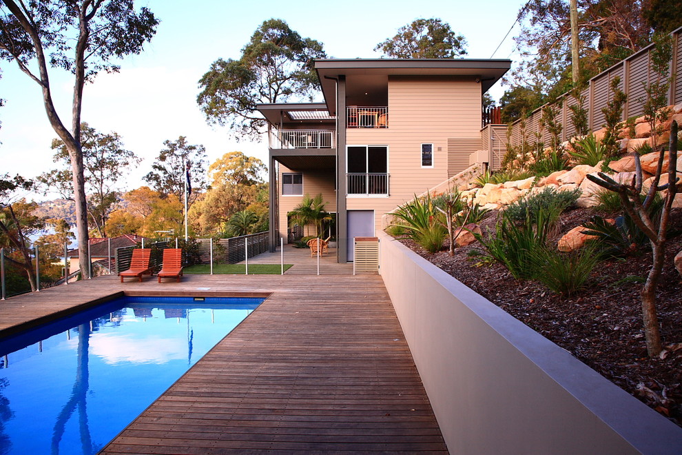 Ejemplo de piscina exótica grande rectangular en patio trasero con entablado