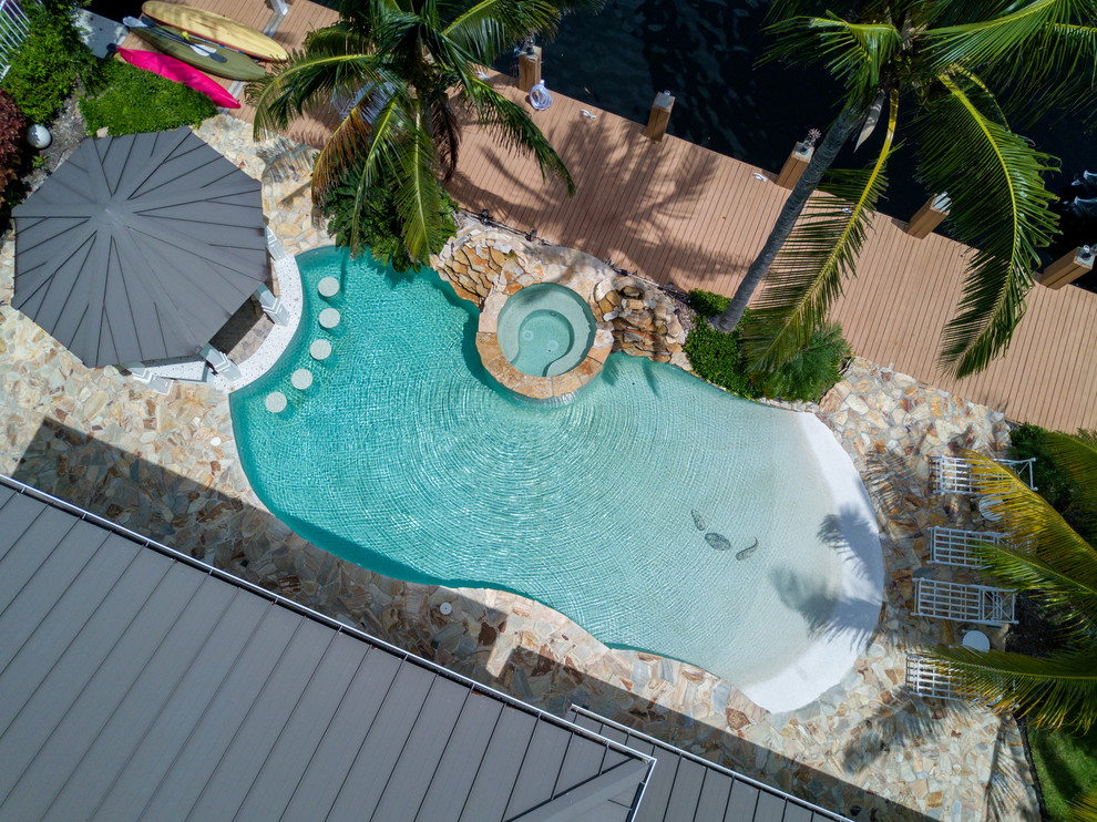 Idee per una piscina naturale costiera personalizzata di medie dimensioni e dietro casa con una vasca idromassaggio e pavimentazioni in pietra naturale