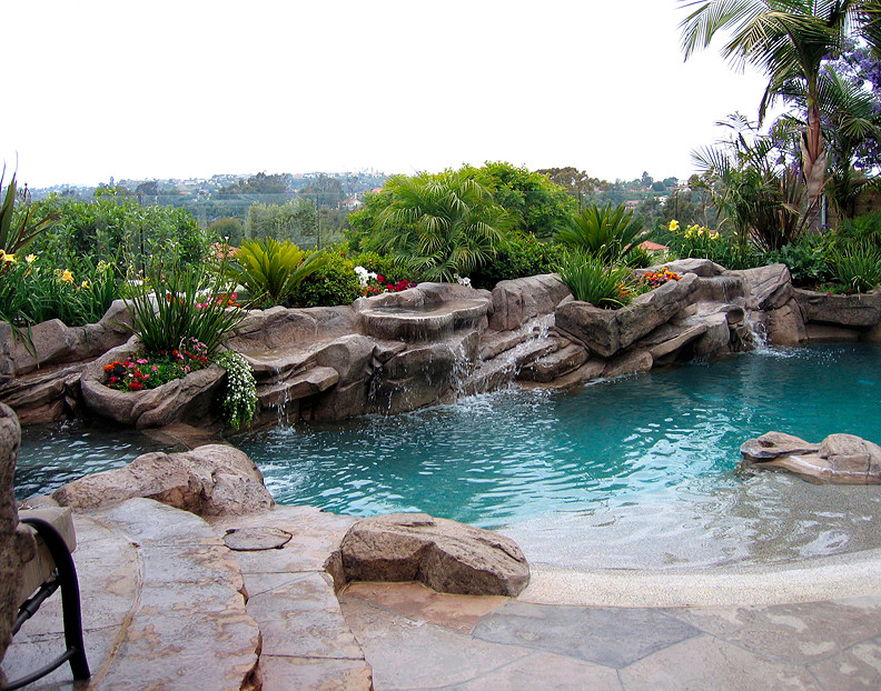 Aménagement d'une piscine arrière exotique sur mesure et de taille moyenne avec un point d'eau et des pavés en pierre naturelle.