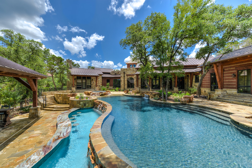 Ispirazione per una grande piscina a sfioro infinito stile rurale personalizzata dietro casa con una vasca idromassaggio e pavimentazioni in pietra naturale