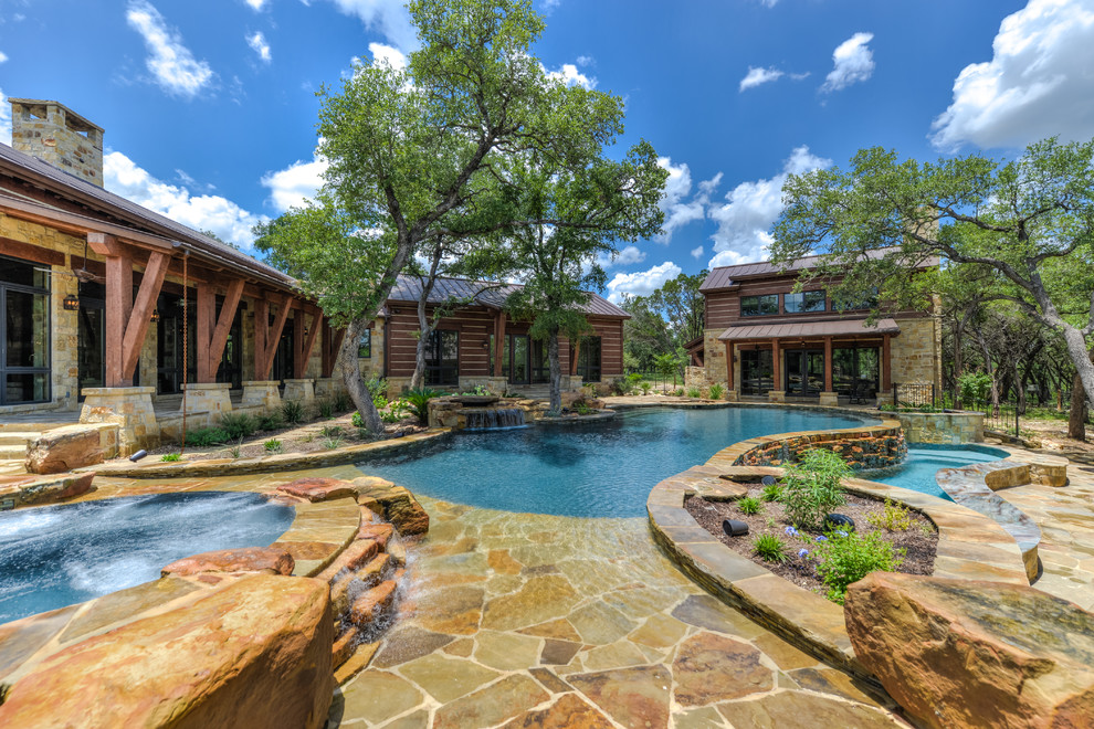 Inspiration for a large rustic backyard stone and custom-shaped infinity hot tub remodel in Austin