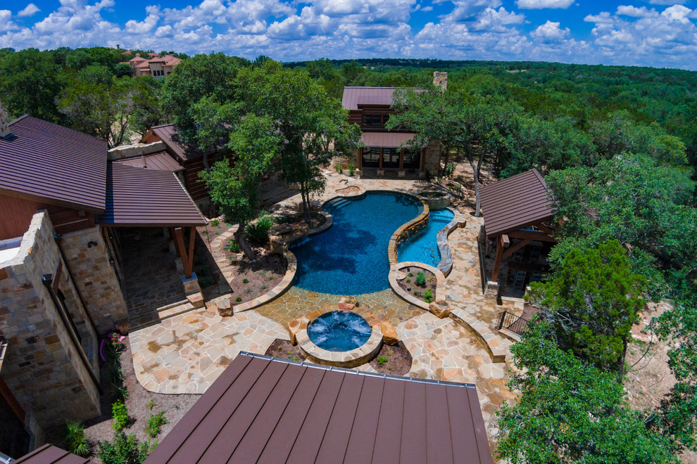 Diseño de piscinas y jacuzzis infinitos rústicos grandes a medida en patio trasero con adoquines de piedra natural