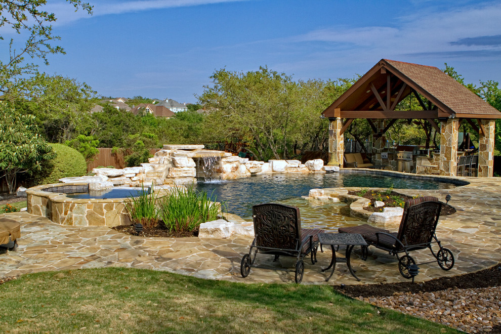 Mid-sized elegant backyard stone and custom-shaped natural hot tub photo in Austin