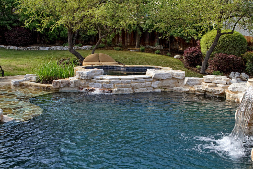 Cette photo montre une piscine naturelle et arrière chic de taille moyenne et sur mesure avec des pavés en pierre naturelle et un bain bouillonnant.