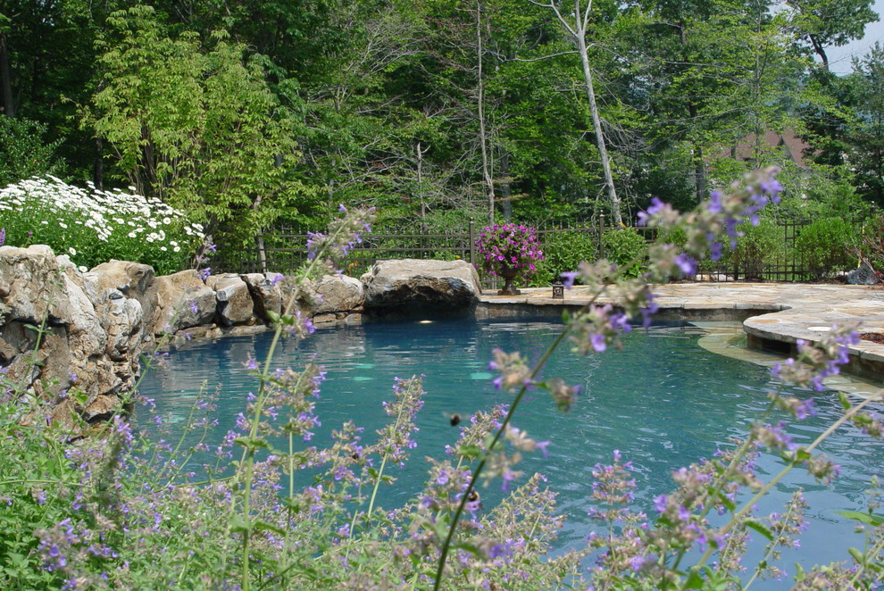 Imagen de piscina con fuente natural tradicional grande a medida en patio trasero con adoquines de piedra natural