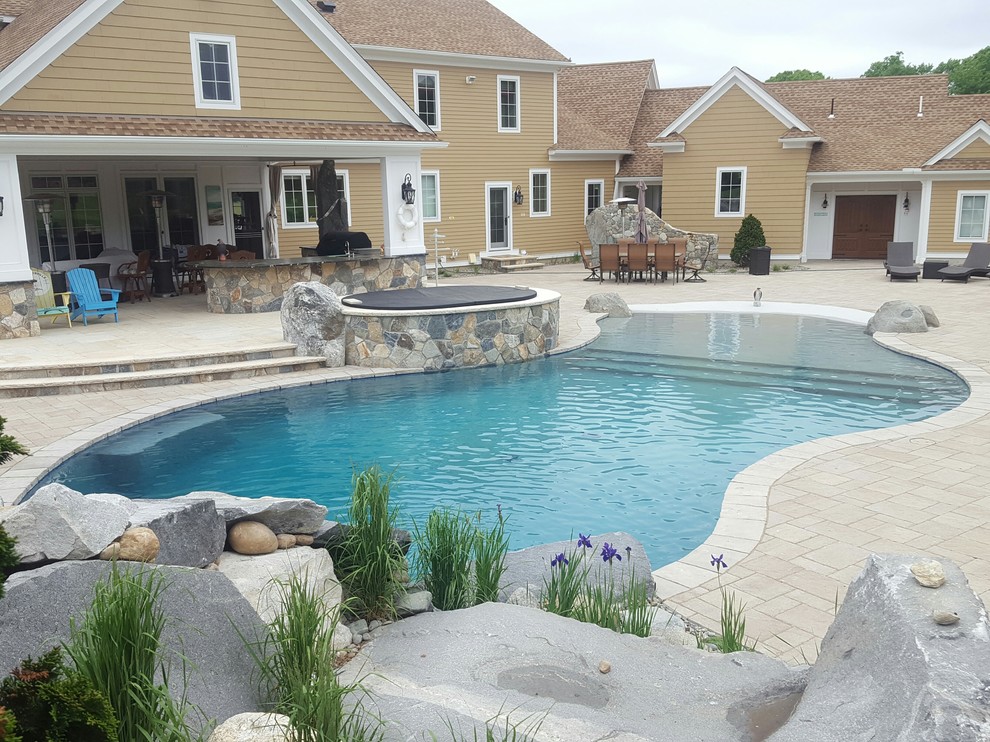 Immagine di una grande piscina naturale costiera personalizzata dietro casa con una vasca idromassaggio