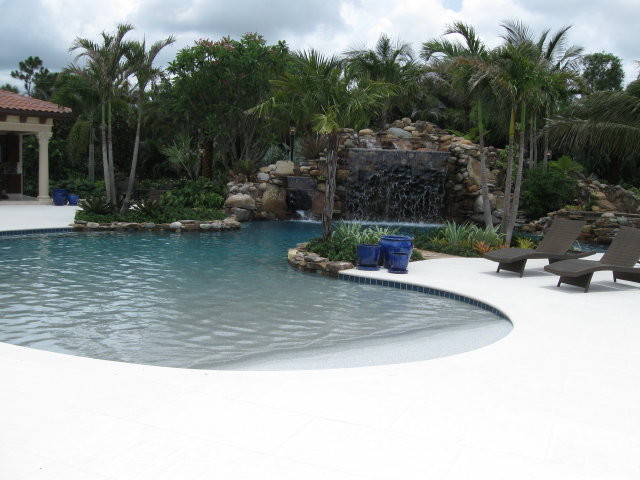 Пример оригинального дизайна: огромный естественный бассейн произвольной формы на заднем дворе в морском стиле с покрытием из бетонных плит