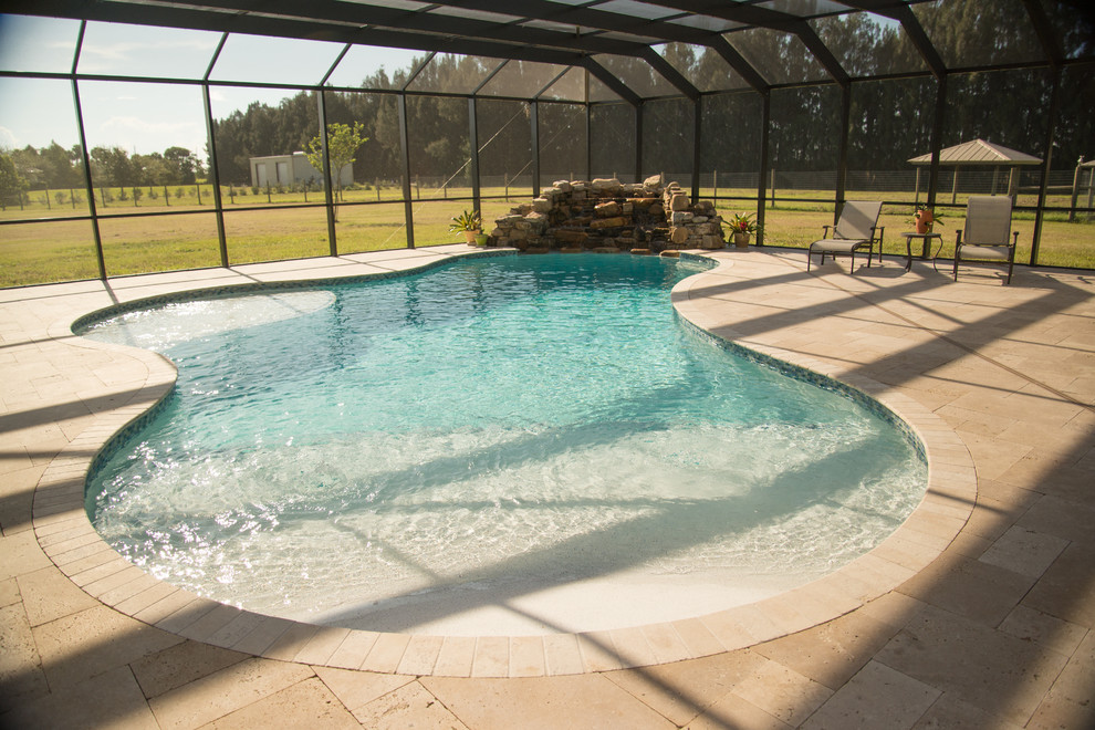 Imagen de piscina natural costera grande a medida en patio trasero con adoquines de piedra natural