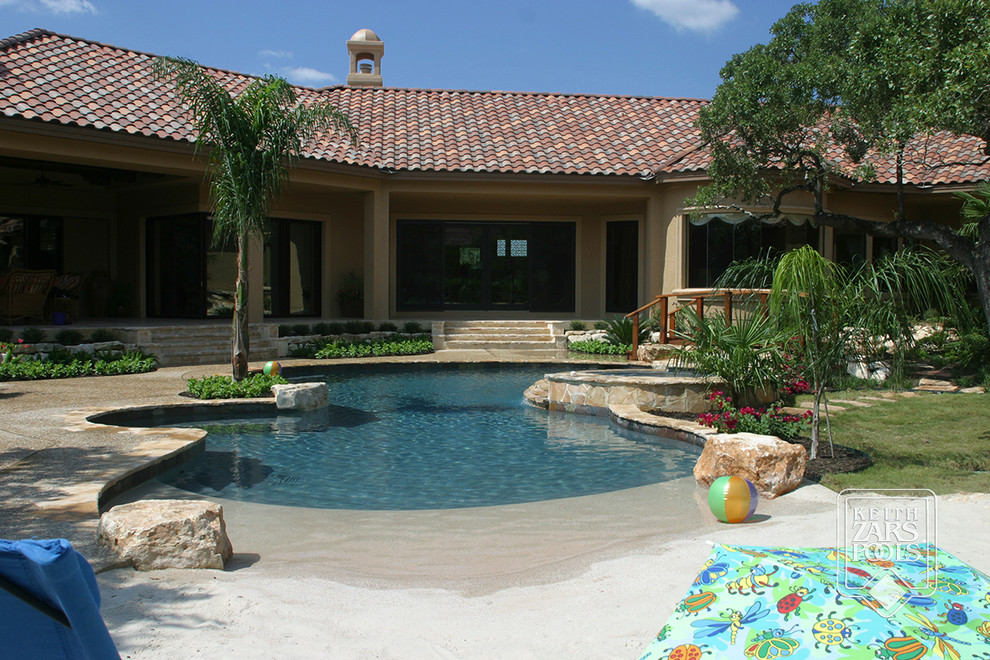 Foto di una piscina naturale stile marino personalizzata di medie dimensioni e dietro casa con pavimentazioni in pietra naturale e una vasca idromassaggio