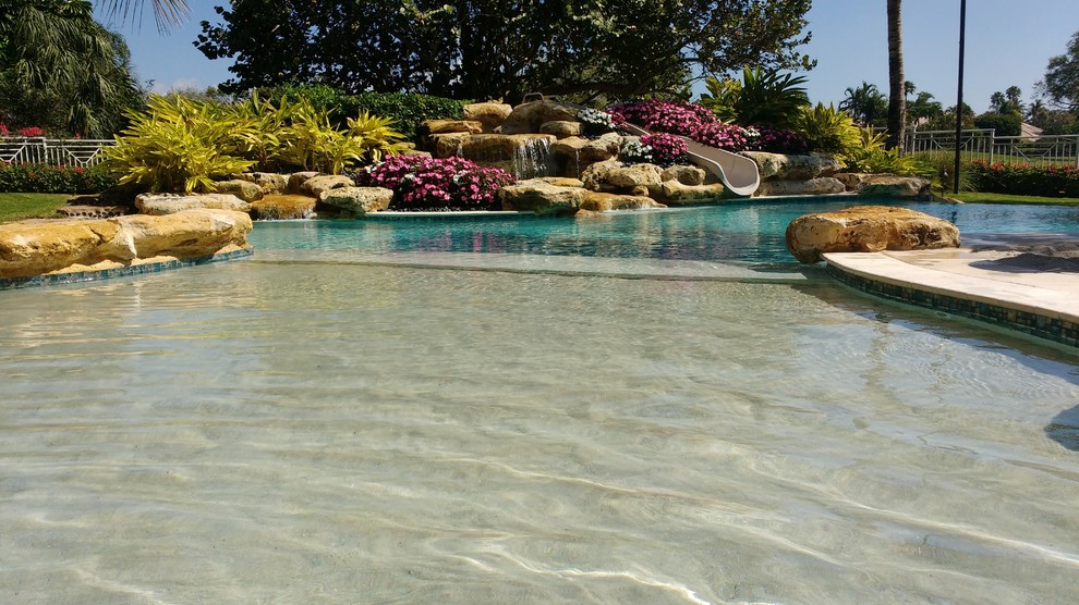 Großer Maritimer Infinity-Pool hinter dem Haus in rechteckiger Form mit Wasserrutsche und Natursteinplatten in Miami