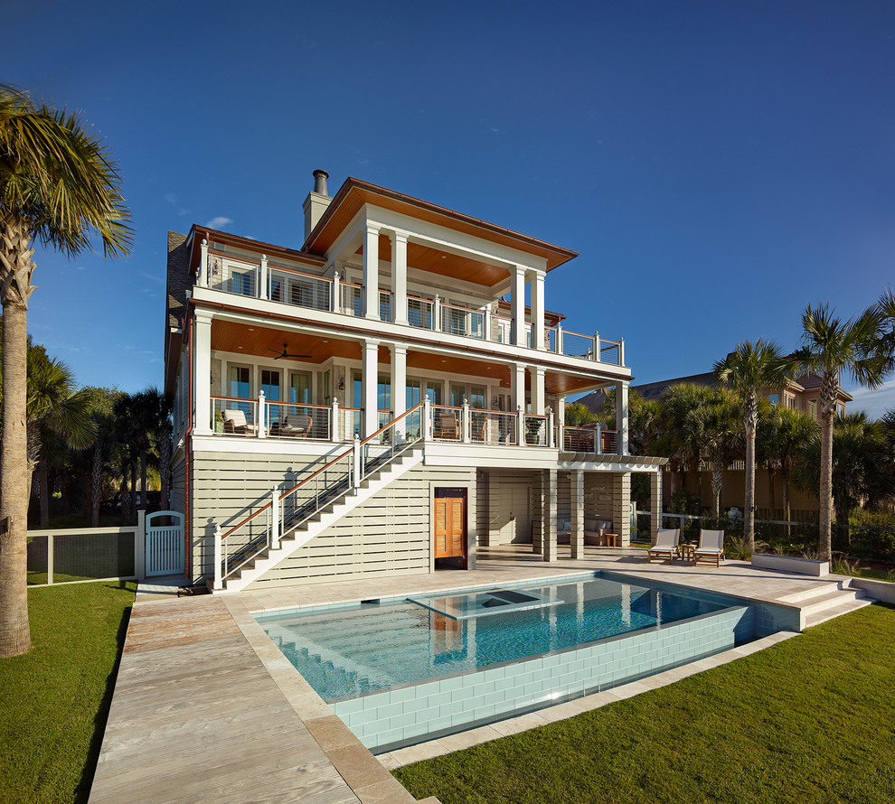 Foto di una piscina a sfioro infinito stile marino rettangolare dietro casa con una vasca idromassaggio e pavimentazioni in pietra naturale