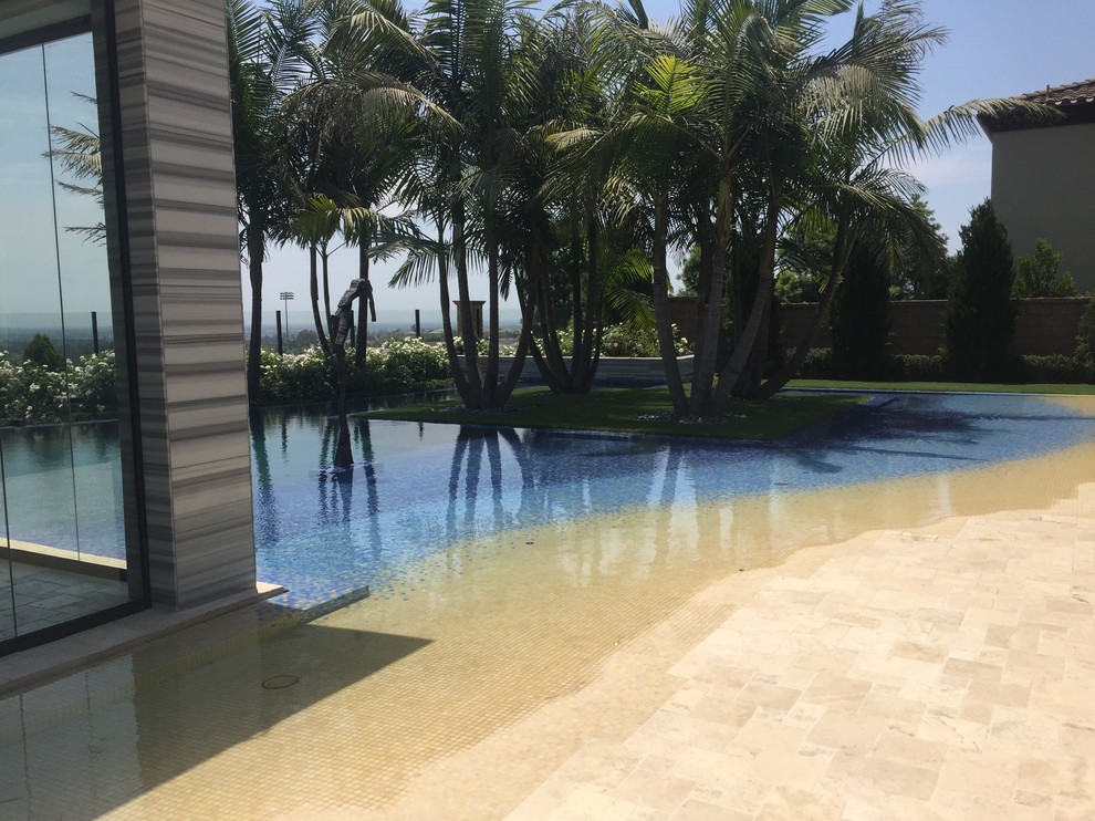Foto di una grande piscina costiera personalizzata dietro casa con fontane e piastrelle